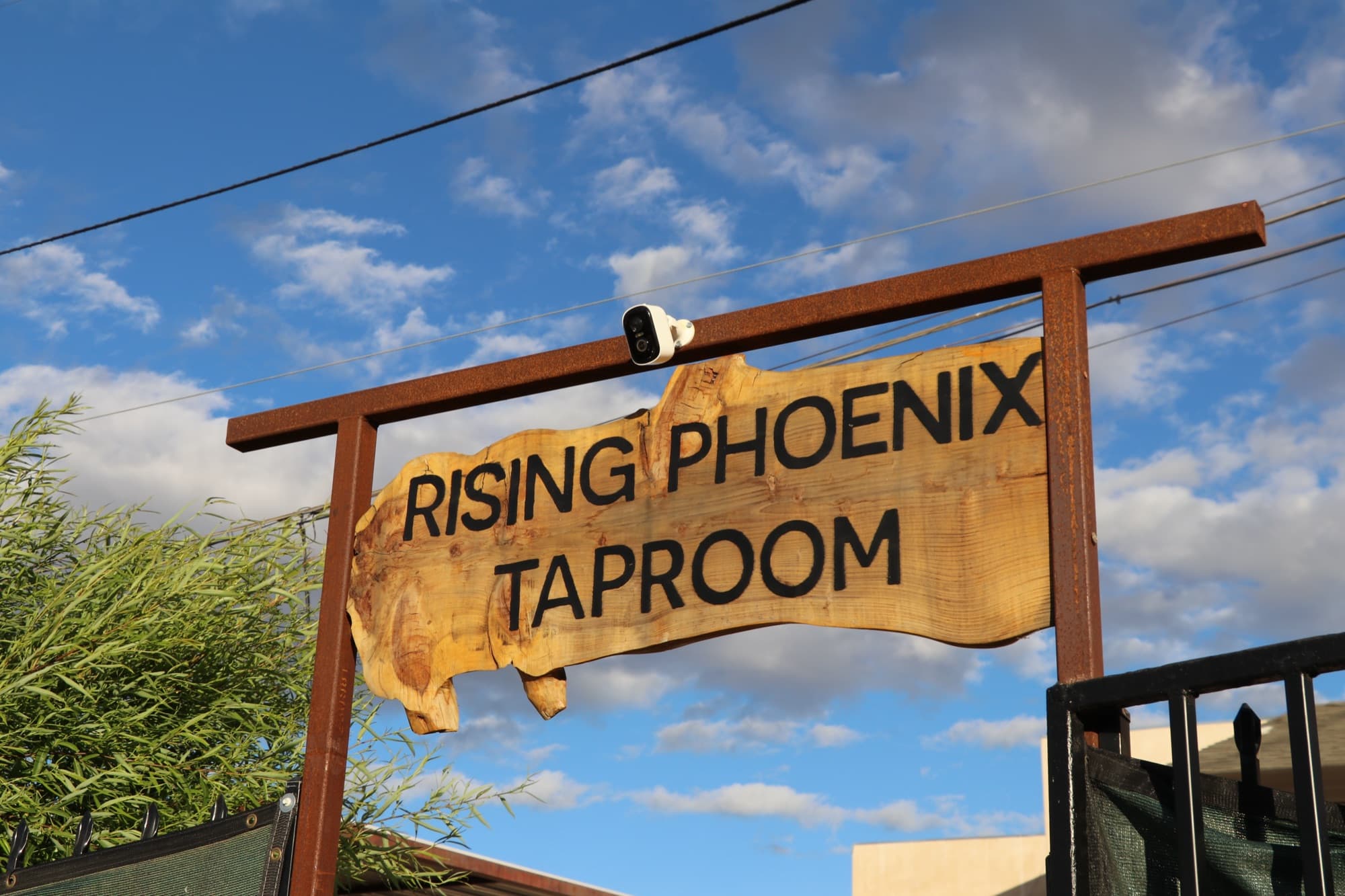The carved wood Rising Phoenix Taproom sign against a blue sky