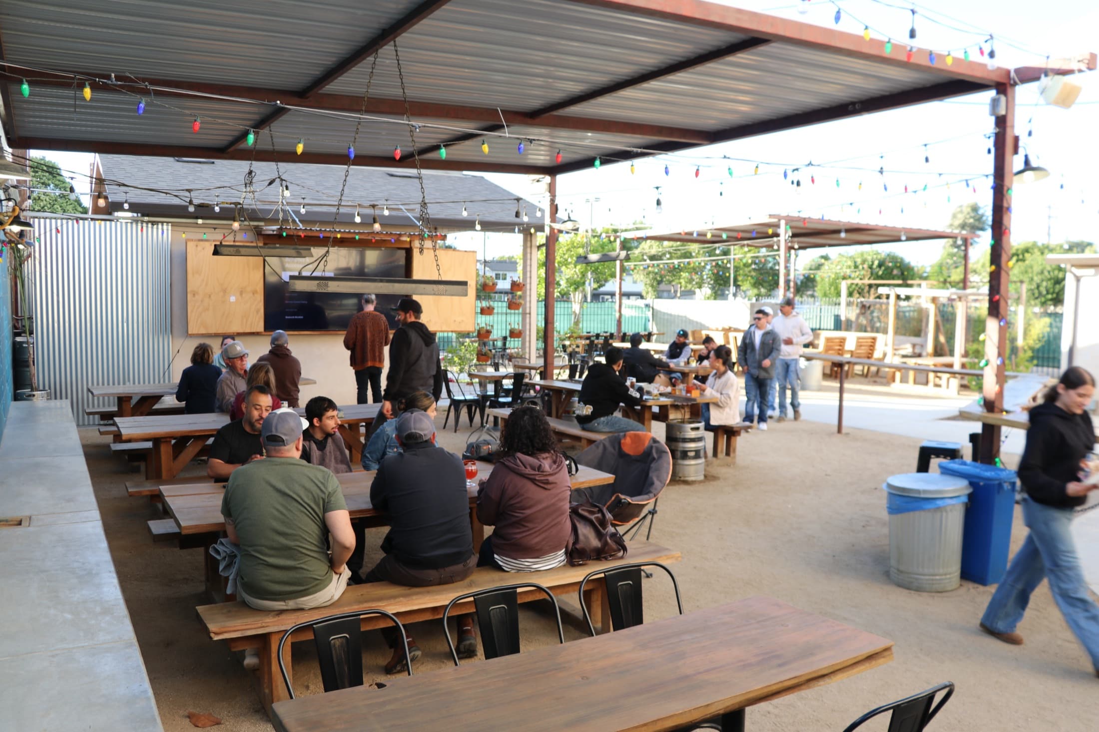 Guests filling the Rising Phoenix beer garden at golden hour under string lights